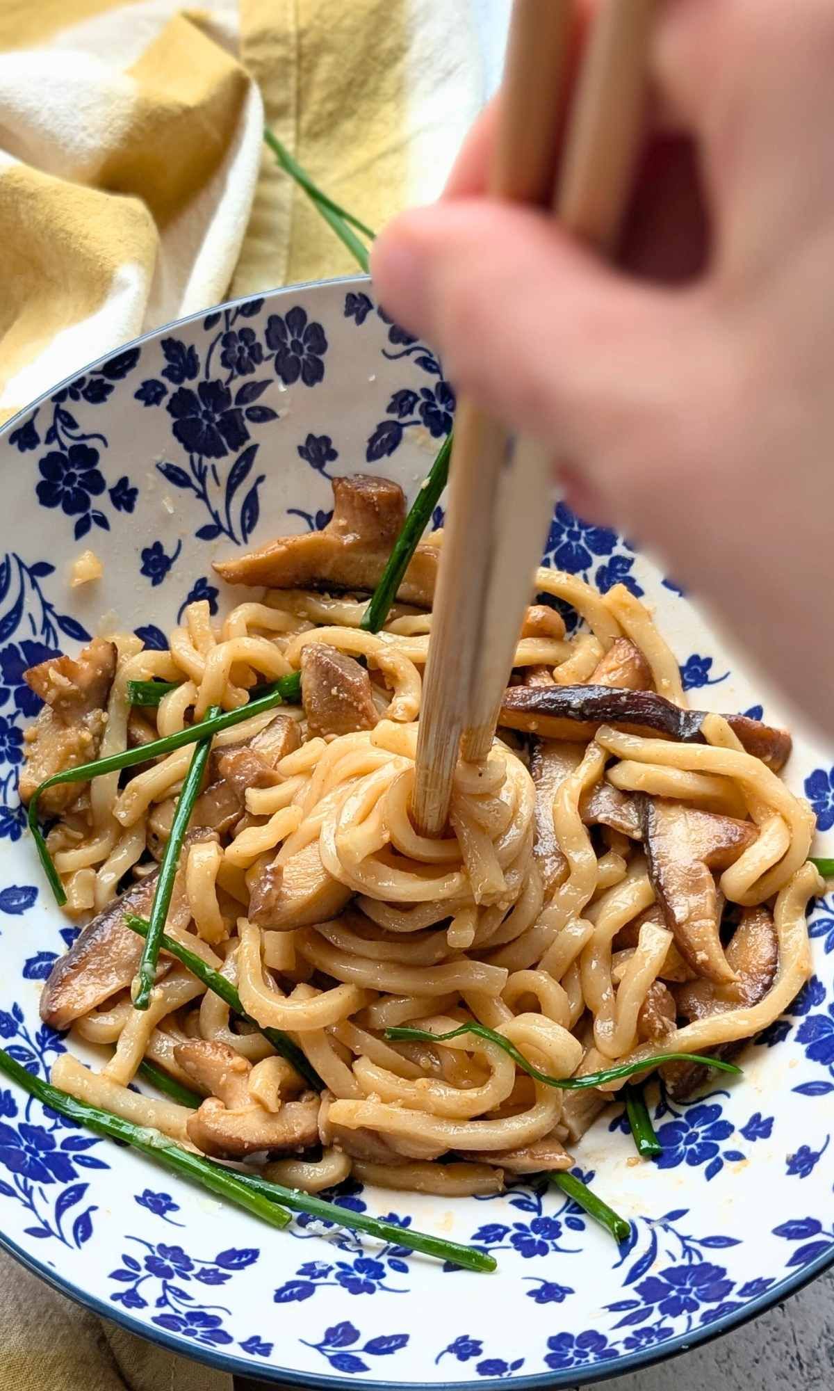chopsticks twirling chinese egg noodles stir fried with shiitake mushrooms and garlic sauce
